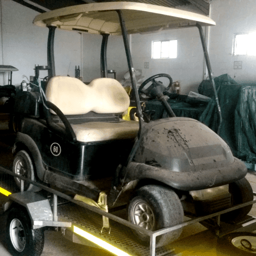 An old, dust-covered 2-seater golf cart, showing signs of wear and dirt before refurbishment