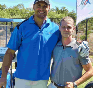 A golf carts and all employee posing with a avid golfer during a golf day.