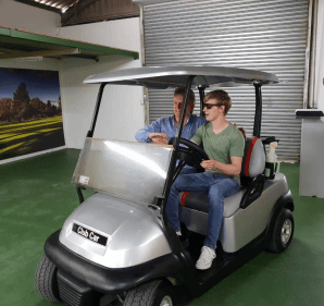 The owner of golf carts and all sitting in a golf cart with his son.