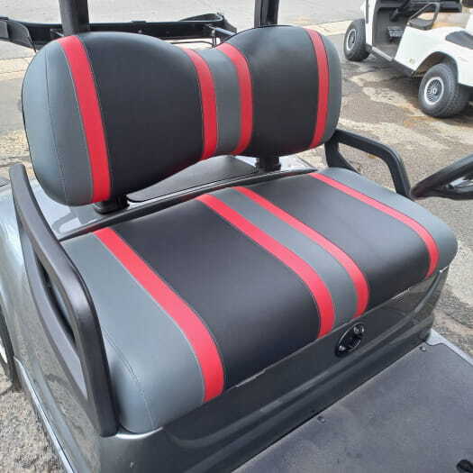 A golf cart with newly refurbished upholstery, featuring a grey seat with a black and red stripe finish