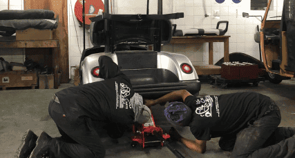 Two Golf Carts & All technicians repairing a golf cart